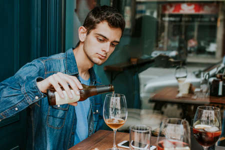 young man on the terrace of the bar drinking beerの写真素材