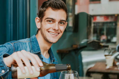 young man on the terrace of the bar drinking beerの写真素材