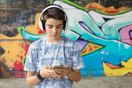 child with headset and phone on the street listening to musicの写真素材