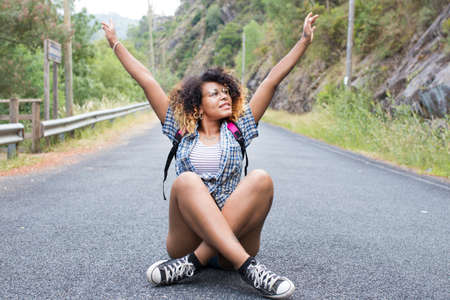 smiling girl sitting on the road with the backpackの写真素材