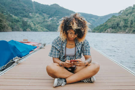 modern young girl with the cellphone on the jettyの写真素材