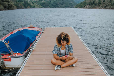 modern young girl with the cellphone on the jettyの写真素材