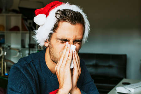 young with christmas clothes sneezingの写真素材