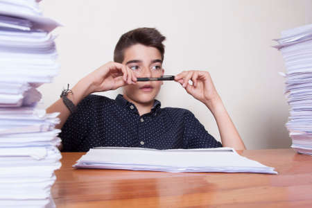 child student on the desk with stacked papersの写真素材