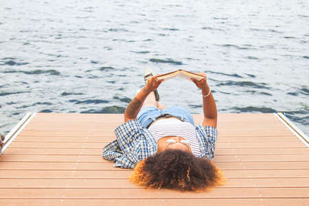 girl with book on the pierの写真素材