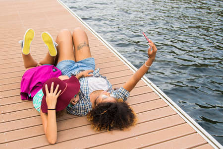 couple of girls at the jetty at sunset from the summer, holidayの写真素材