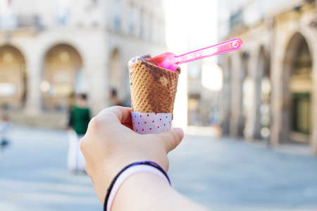 hand with the ice cream in the foreground