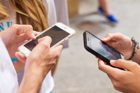 A group of young people with mobile phones on the street