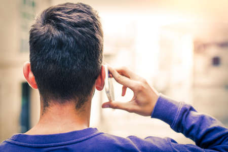 young on his back talking on mobile phone on the streetの写真素材