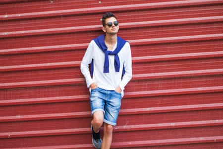 Fashionable teenager on the wall of the streetの写真素材