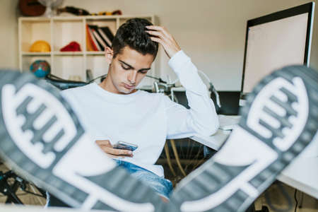 teenager or young man student on the desktop with the mobile phone and computerの写真素材