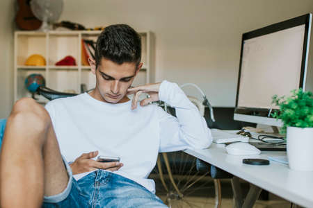 teenager or young man student on the desktop with the mobile phone and computerの写真素材