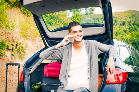 young man with mobile phone in the car
