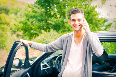young man with mobile phone in the car