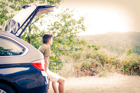 child in the trunk of the car looking at the landscapeの写真素材