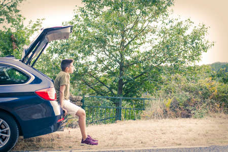 child in the trunk of the car looking at the landscapeの写真素材