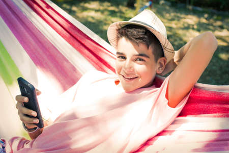 child with mobile phone in the hammock in summer