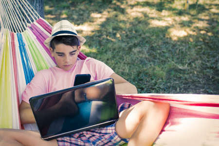 child with mobile phone in the hammock in summer