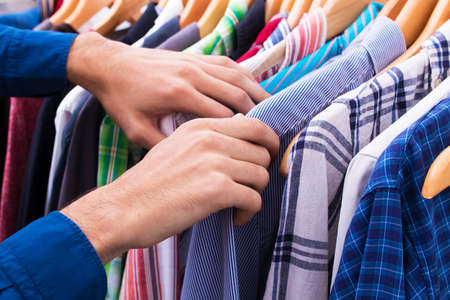 hands in the clothes shop looking at the hangersの写真素材