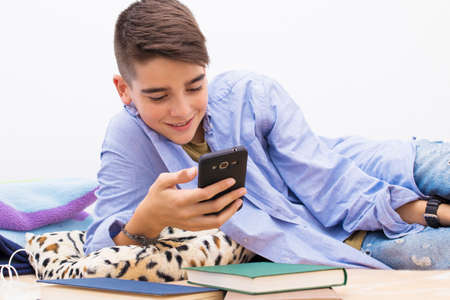 child with a mobile phone lying at homeの写真素材