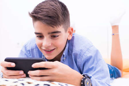 child with a mobile phone lying at home