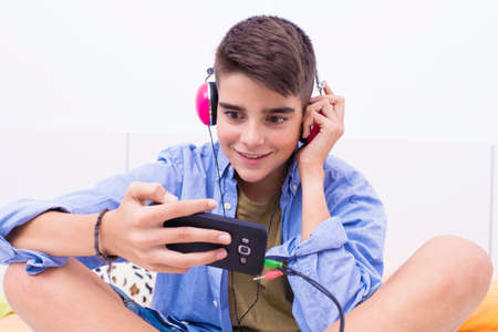teenage boy with mobile phone and headphones listening to music