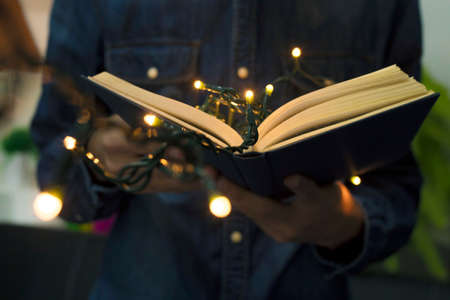 open book in the hands with the christmas lightsの写真素材