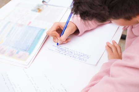 child's hand studying and writing on the school desk or homeの写真素材