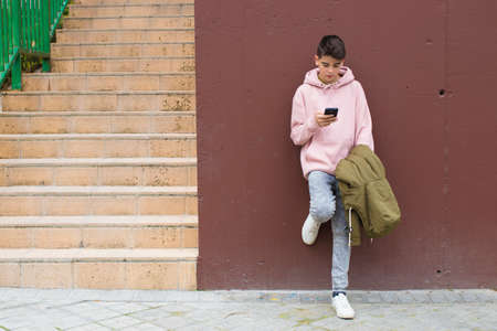 child with the mobile phone on the wall of the city street, teenagersの写真素材