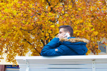 young with mobile phone in the park in autumnの写真素材