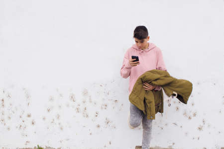 young teenager with mobile phone on the wall of the city street
