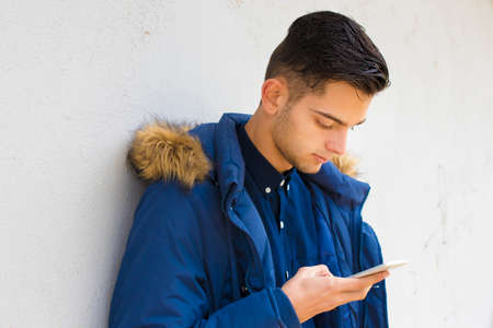 young with mobile phone on the wall of the city streetの写真素材