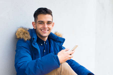 young with mobile phone on the wallの写真素材