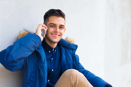 young with mobile phone on the wallの写真素材