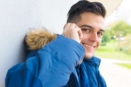 young with mobile phone on the wallの写真素材