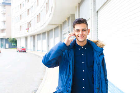 young man talking on mobile phone on city streetの写真素材