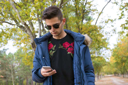 young with mobile phone in the fall outdoors