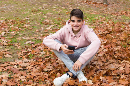 preteenage boy with mobile phone in the woods in the fallの写真素材