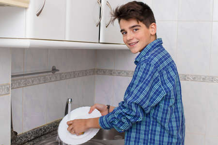 boy, young, teenager or preteen scrubbing the dishesの写真素材