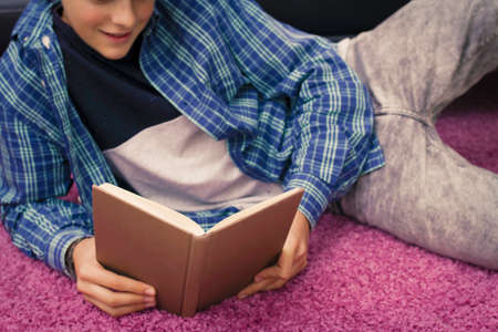 child, teenager or preteen reading or studying at homeの写真素材