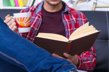 young adult or teenager reading a book at homeの写真素材