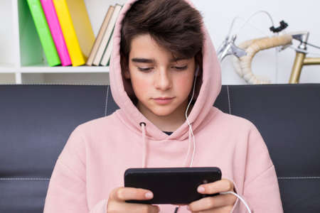 teenager or preteen with mobile phone on the sofa at home