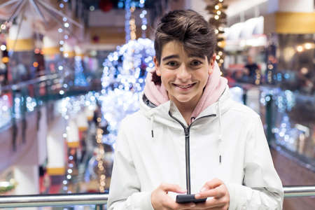 teenage boy or preteen with mobile phone at christmas