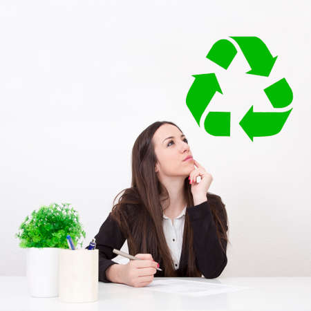 thoughtful business woman with recycling symbolの写真素材