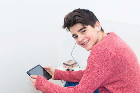 teenager with the tablet and headphones listening to musicの写真素材