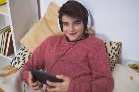 teenager at home with headphones and tablet