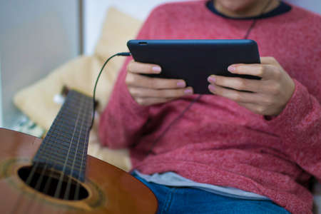 young man with computer and guitar in house roomの写真素材