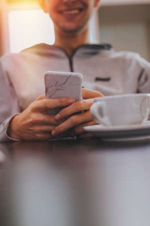 hand closeup with mobile phone and coffee cupの写真素材