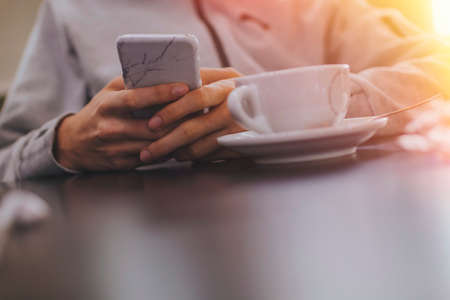 hand closeup with mobile phone and coffee cupの写真素材