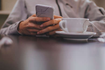 hand closeup with mobile phone and coffee cupの写真素材